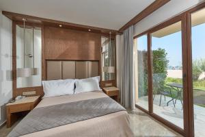 a bedroom with a bed and a large window at Mediterranean Village Hotel & Spa in Paralia Katerinis