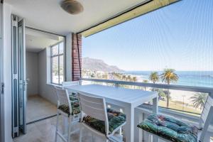 balcón con mesa, sillas y vistas al océano en Beach Vista by Totalstay, en Ciudad del Cabo
