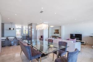 a dining room and living room with a glass table and chairs at Beach Vista by Totalstay in Cape Town