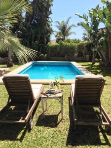 two chairs and a table next to a swimming pool at Las Gitanillas, villa with heated pool, La Cala de Mijas in Mijas Costa