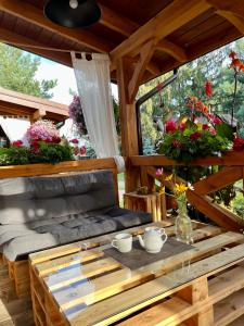 - une terrasse couverte avec une table et des fleurs dans l'établissement Domek Siedlisko Poleski Zakątek, à Sosnowica