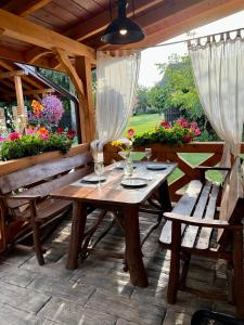 une table en bois et des bancs sur une terrasse fleurie dans l'établissement Domek Siedlisko Poleski Zakątek, à Sosnowica