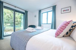 a bedroom with a large white bed with a window at Little Bramble, Orford in Orford