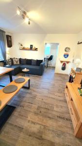 sala de estar con sofá azul y suelo de madera en FRANKES LODGE Apartment mit Garten und Pool, 6 Einzelbetten, en Essen