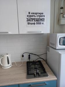 a kitchen counter with a stove and a microwave at Астана 3 in Oral