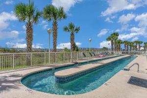 una piscina con palmeras y una valla en Crescent Shores 911 Condo, en North Myrtle Beach