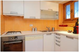 a kitchen with white cabinets and an orange tiled wall at [Casa Quadrifoglio] a 3 minuti dalle piste da sci in Gressoney-Saint-Jean