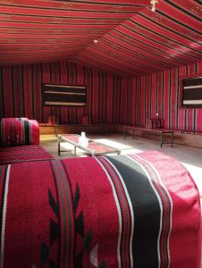 a red room with a bed and a table at Sunset Mountain in Wadi Rum
