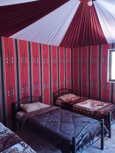 two beds in a room with a red wall at Sunset Mountain in Wadi Rum