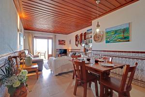 een woonkamer met een houten plafond en een eettafel bij Monte Gordo Beachview 2 by Homing in Monte Gordo