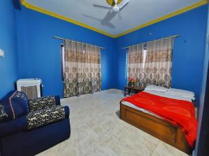 ein Schlafzimmer mit blauen Wänden und einem Bett und einem Sofa in der Unterkunft Tathāgata Homestay in Rummindei