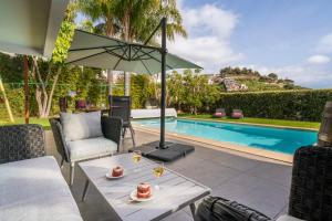 a patio with a table with a umbrella and a pool at Villa das Quebradas by An Island Apart in Funchal