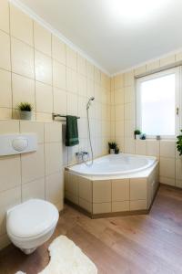 uma casa de banho com uma banheira, um WC e uma janela. em Csendes, modern, otthonos társasházi lakás em Zalacsány
