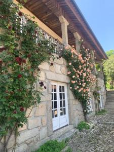 a stone building with flowers on the side of it at Casa dos três rapazes in Monte Córdova