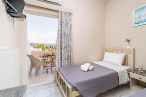 a bedroom with a bed and a balcony at Filia Apartments in Pitsidia