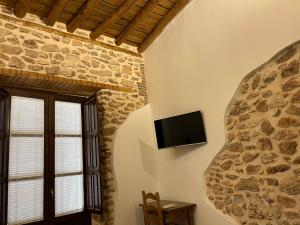 a living room with a tv on a stone wall at El Carmen in Benalúa de Guadix