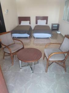 a room with two beds and a table and chairs at Djibguesthouse in Djibouti