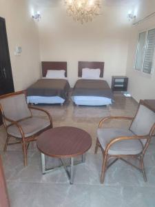 Cette chambre comprend deux lits, une table et des chaises. dans l'établissement Djibguesthouse, à Djibouti