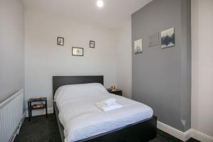 a bedroom with a bed with white sheets on it at Cozy 3 bedroom house @ Hömli in Loughborough