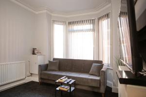 a living room with a couch and two windows at Cozy 3 bedroom house @ Hömli in Loughborough
