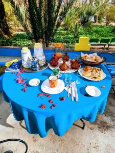 una mesa azul con comida en la playa en Riad Tagmadarte Ferme d'Hôte en Zagora