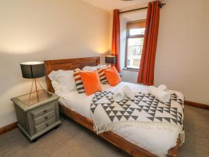 カークビー・ロンズデールにあるOld Farm Cottageのベッドルーム1室(オレンジ色の枕と窓付)
