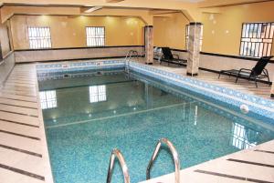 a large swimming pool in a hotel with blue water at Enclave Hotel Abuja in Kagini
