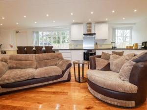 a living room with two couches and a kitchen at Carew Lodge & Loft in Torpoint