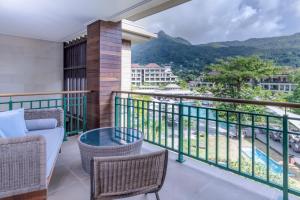 uma varanda com um sofá e cadeiras e uma vista em Savoy Seychelles Resort & Spa em Beau Vallon
