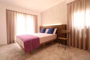 Un dormitorio con una cama con almohadas azules y una ventana en 102 I Posada del Mar I Encantador hostel en la playa de Gandia, en Los Mártires