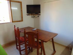 a dining room table with two chairs and a television at Aldea Serrana in Tandil