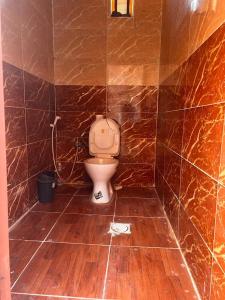 La salle de bains est pourvue de toilettes et d'un mur carrelé marron. dans l'établissement Sunset Mountain, à Wadi Rum