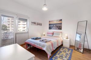 a white bedroom with a bed and a mirror at The Beach Place in Costa da Caparica