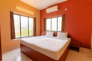 a bedroom with orange walls and a bed with two windows at FabHotel Amar Raj Inn in Kolkata