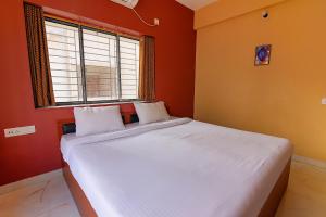 a bedroom with a bed with white sheets and a window at FabHotel Amar Raj Inn in Kolkata