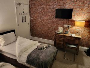 a bedroom with a bed and a desk with a television at The Jubilee Inn - Bar & Kitchen in Litherland
