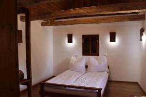 um quarto com uma cama com lençóis brancos e almofadas em Salaš u Bregu in Cheile Carasului em Caraşova