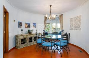 a dining room with a glass table and blue chairs at Quinta do Vale Formoso in Armação de Pêra