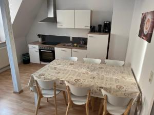 a kitchen with a table with white chairs and a kitchen with white cabinets at Gästehaus Graupner-Mittweida in Mittweida