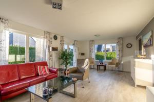 sala de estar con sofá rojo y mesa en Villapark Kamperfoelie 77, en De Koog