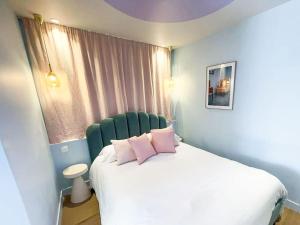 a bedroom with a white bed with pink pillows at Appartement Aquaroom RDC - Plage 50m - Rue gratuite in Saint Malo