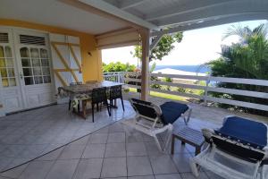 un portico con tavolo, sedie e vista sull'oceano di Bungalow with sea view in Deshaies a Deshaies Altre 3 foto