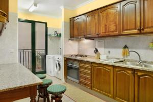 a kitchen with wooden cabinets and green bar stools at Palheiro Residence Familiar 2 in Funchal