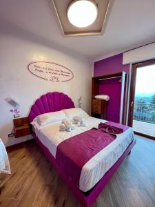a large bed with a purple headboard in a room at Rainbow Hotel Depandance Joli in San Marino