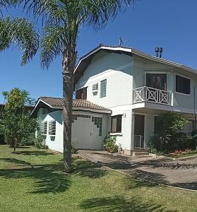 una casa blanca con una palmera delante de ella en Casa eco para você e seu pet!, en Canela