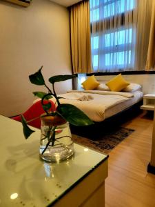 Lovita Hotel Kuantan في كُوانتان: غرفة بسرير و مزهرية زجاجية مع نبات
