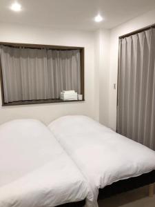 東京的住宿－Oku Apartment，卧室设有两张床铺、镜子和窗户