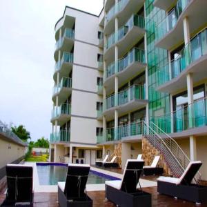 a large apartment building with chairs and a swimming pool at Paradise Appartment hotel in Mutumba