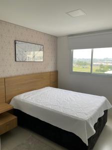 a bedroom with a large bed and a window at Apartamento 2 quartos c/ Piscina 3 Ar-condicionado in Torres