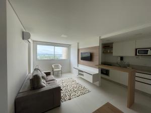 a living room with a couch and a kitchen at Apartamento 2 quartos c/ Piscina 3 Ar-condicionado in Torres